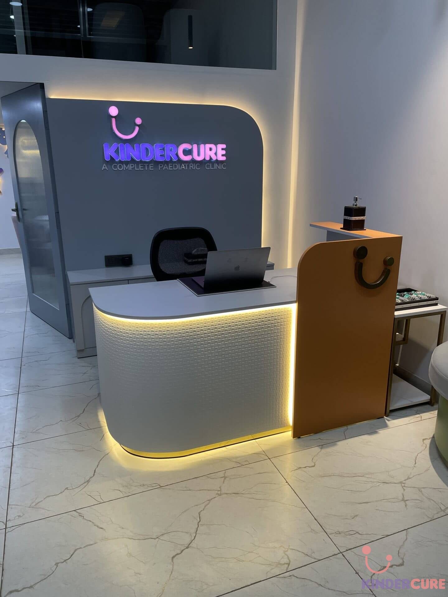 Reception desk at KinderCure Paediatric Clinic featuring the KinderCure's logo on the back wall in Gurgaon